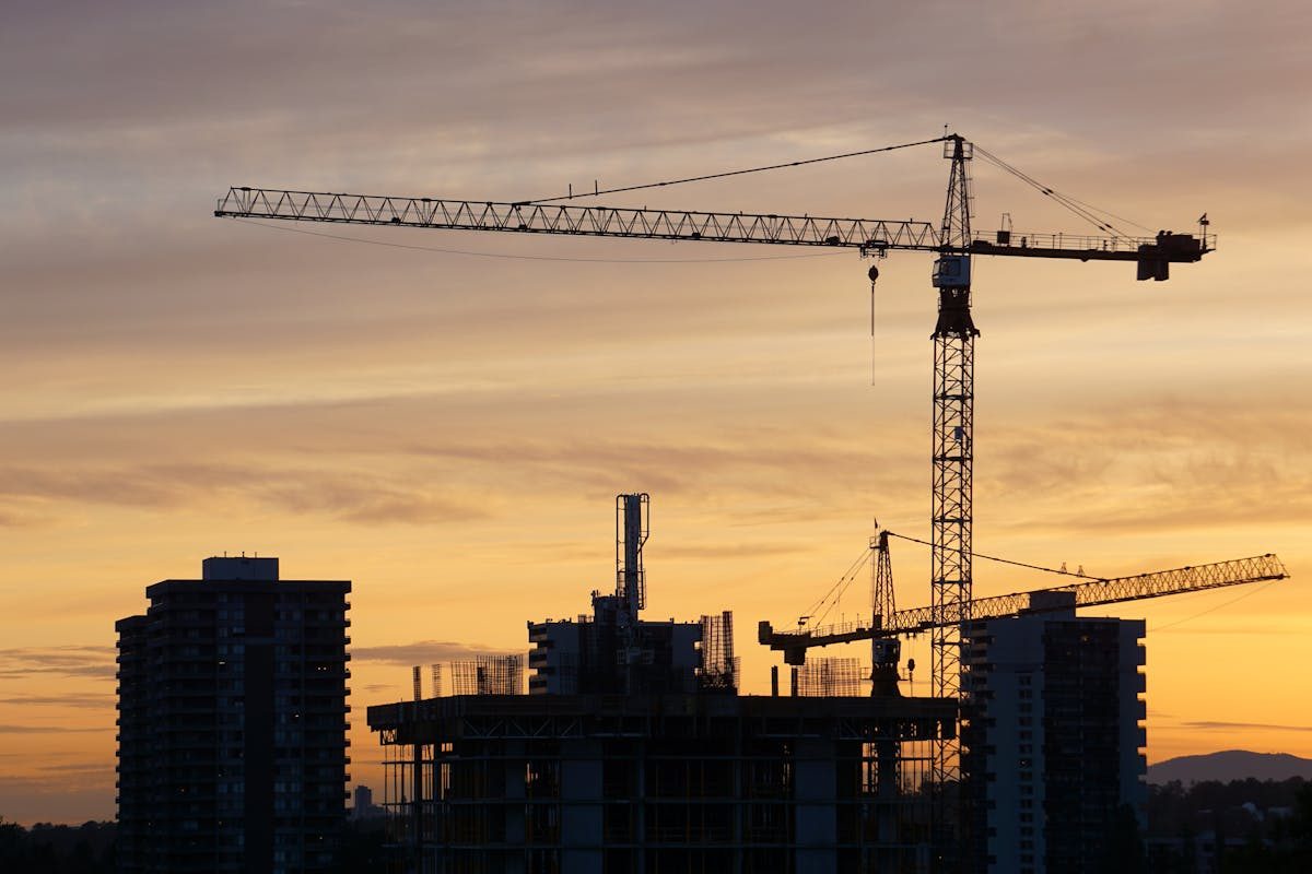 Construction cranes at golden hour, building the capital stack